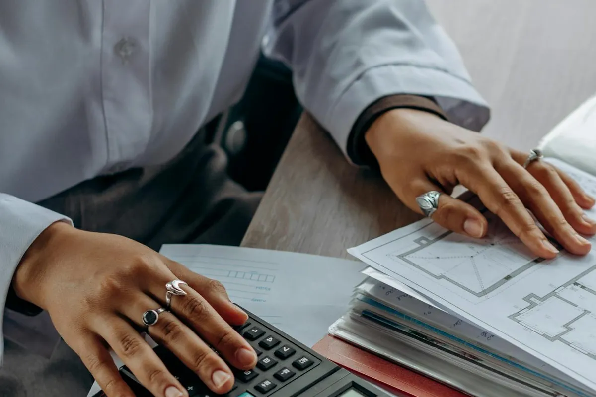 Homeowner reviewing roof insurance policy documents at kitchen table with calculator