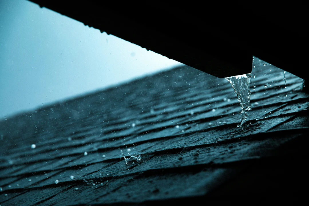 Water stain on ceiling with bucket placed underneath to catch drips from active roof leak